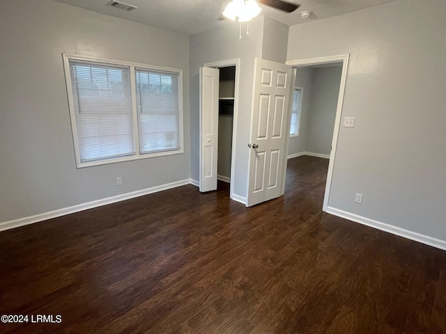 unfurnished bedroom with dark wood-type flooring, a closet, and ceiling fan