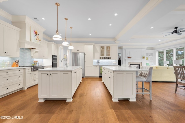 kitchen with hanging light fixtures, tasteful backsplash, a kitchen island with sink, and stainless steel appliances