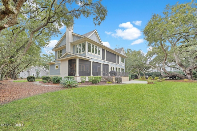 rear view of property featuring a sunroom and a yard