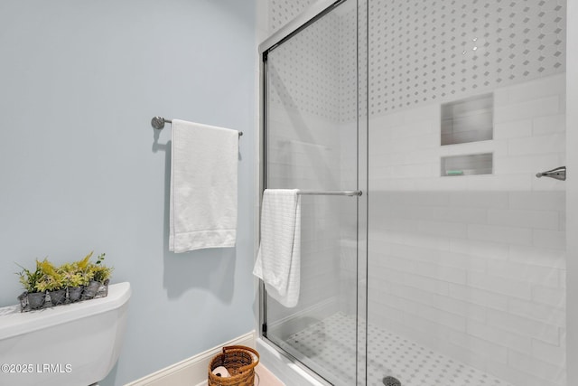 bathroom featuring toilet and a shower with shower door