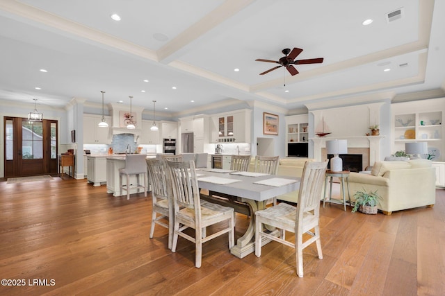 dining room with sink, beam ceiling, ceiling fan, and light wood-type flooring