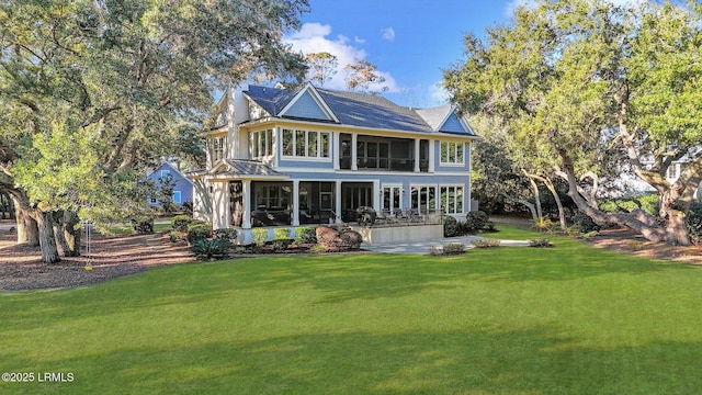 back of property with a sunroom and a lawn