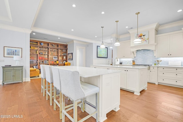 kitchen featuring sink, white cabinetry, hanging light fixtures, a kitchen island, and backsplash