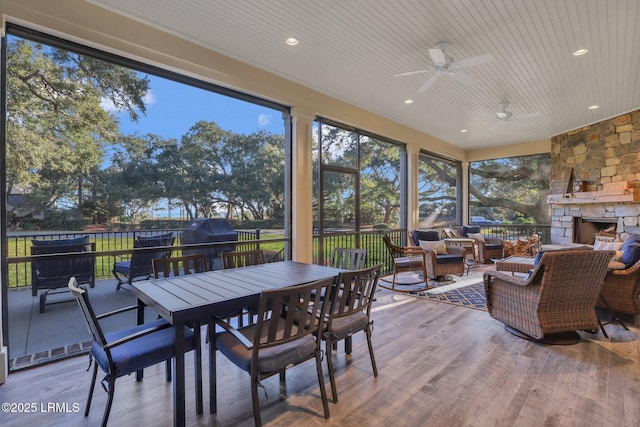 sunroom / solarium with ceiling fan and an outdoor stone fireplace