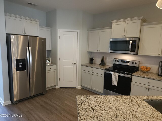 kitchen with light stone counters, appliances with stainless steel finishes, tasteful backsplash, and white cabinets