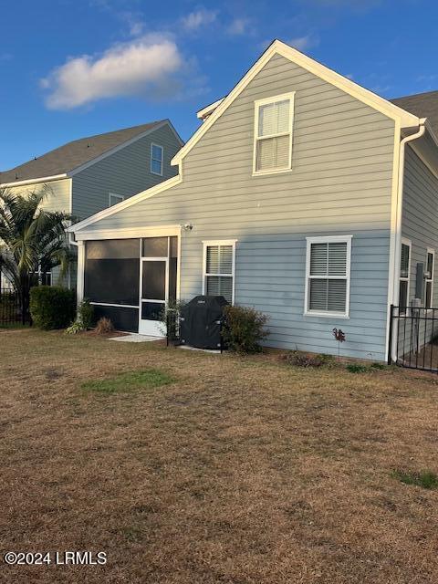 back of house with a sunroom and a lawn