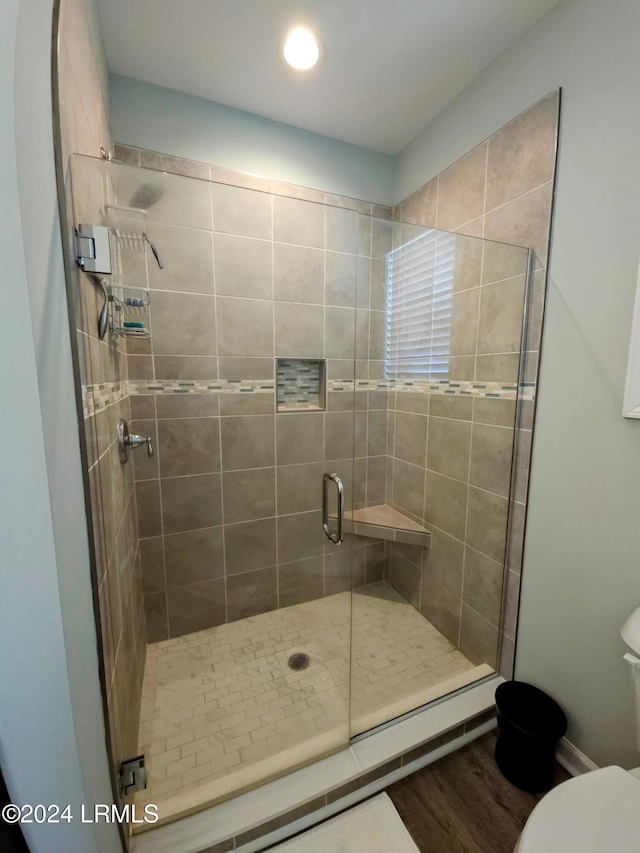 bathroom with wood-type flooring, toilet, and an enclosed shower