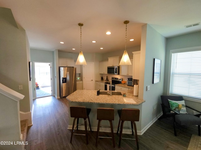 kitchen with decorative light fixtures, a wealth of natural light, white cabinets, and appliances with stainless steel finishes