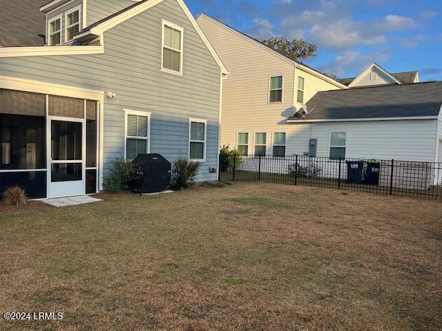 back of property with a sunroom and a lawn