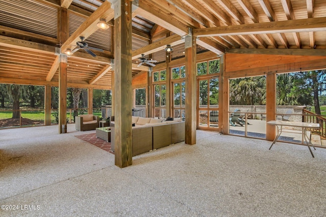 unfurnished sunroom featuring ceiling fan, a healthy amount of sunlight, and vaulted ceiling with beams