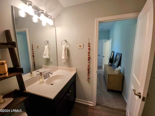 bathroom featuring vanity, vaulted ceiling, wood-type flooring, and a notable chandelier