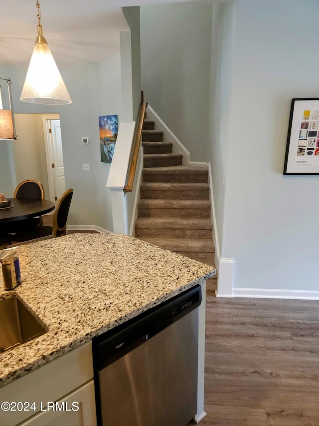 kitchen with sink, light stone counters, stainless steel dishwasher, dark hardwood / wood-style flooring, and pendant lighting