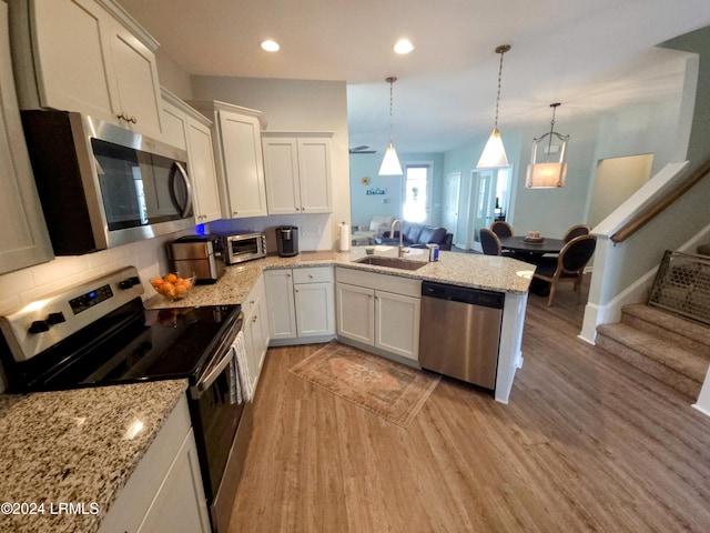 kitchen with sink, white cabinetry, decorative light fixtures, light hardwood / wood-style flooring, and appliances with stainless steel finishes