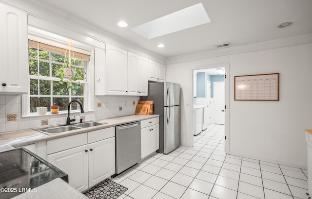 27 Tulifinny Ln, Yemassee, SC 29945 - kitchen featuring appliances with stainless steel finishes, crown molding, washing machine and dryer, white cabinetry, and decorative backsplash