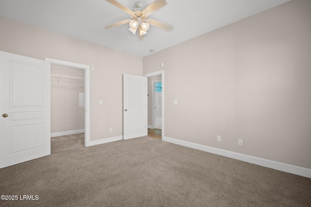 unfurnished bedroom featuring a spacious closet, a closet, ceiling fan, and carpet