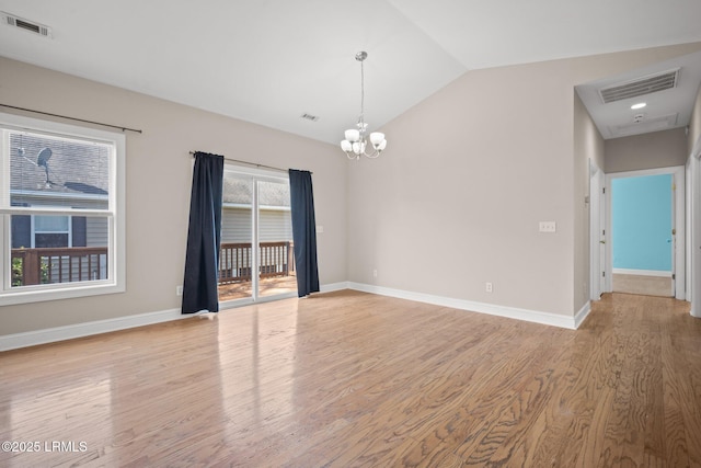 empty room with a notable chandelier, vaulted ceiling, and light hardwood / wood-style floors