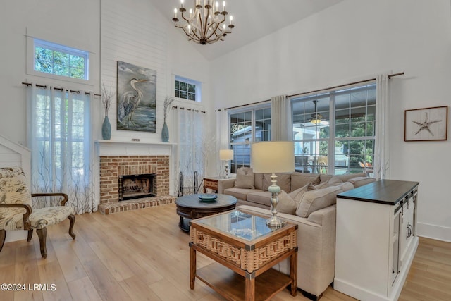 living room featuring a fireplace, high vaulted ceiling, a healthy amount of sunlight, and light wood-type flooring