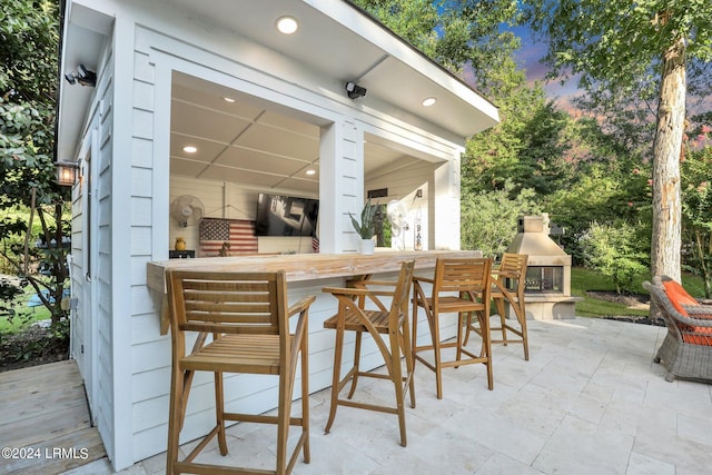 view of patio / terrace featuring a bar and exterior fireplace