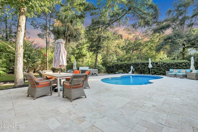 pool at dusk featuring an outdoor hangout area and a patio area