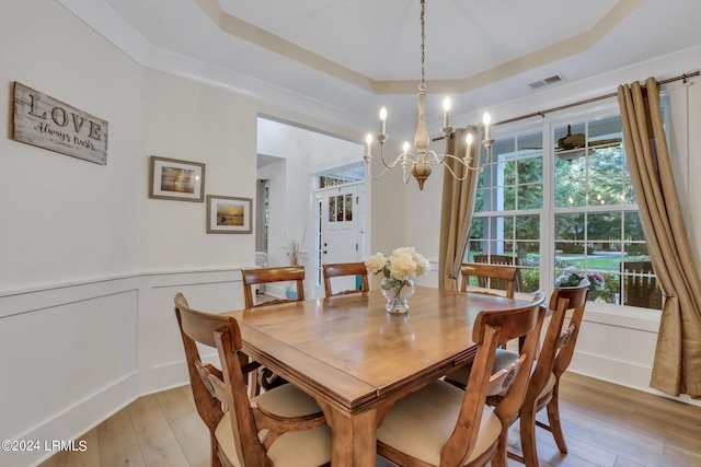 dining area with a tray ceiling, plenty of natural light, and light wood-type flooring