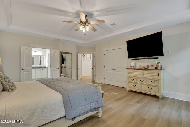 bedroom with ceiling fan, a tray ceiling, and light wood-type flooring