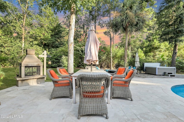 patio terrace at dusk featuring a multi sided fireplace