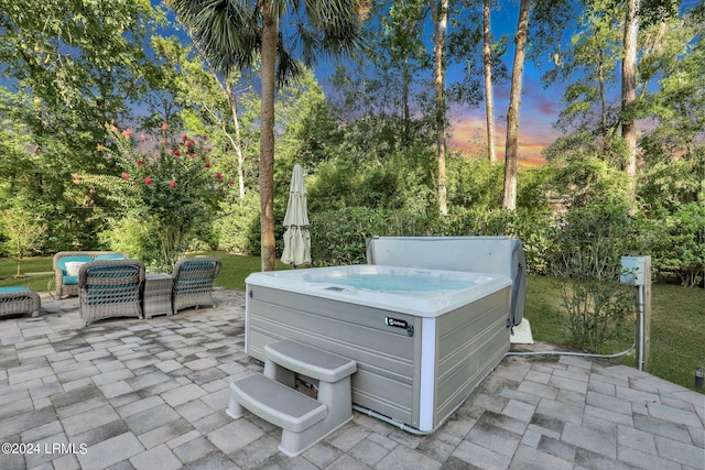 patio terrace at dusk featuring a hot tub