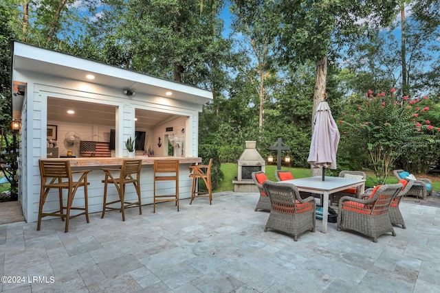 view of patio / terrace featuring a bar and an outdoor stone fireplace