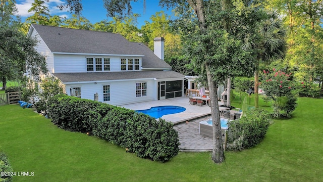 back of property with an outdoor living space, a lawn, a sunroom, and a patio area