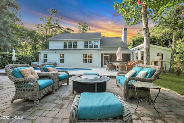 back house at dusk with a patio and an outdoor living space with a fire pit