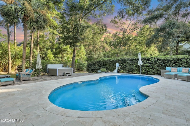 pool at dusk with a hot tub, a patio, and outdoor lounge area