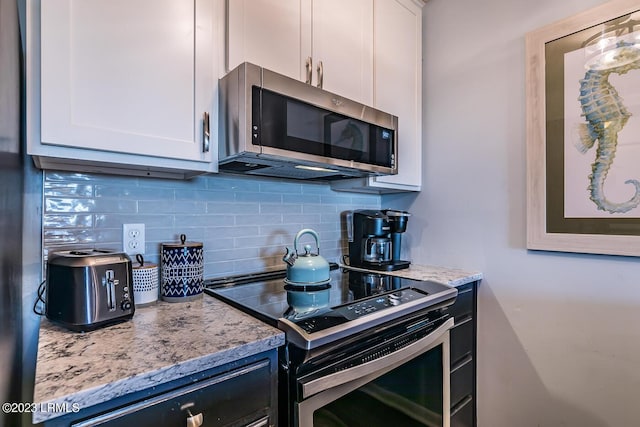 kitchen with light stone counters, backsplash, stainless steel appliances, and white cabinets