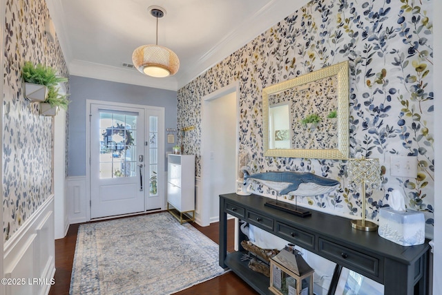 entrance foyer with a wainscoted wall, wood finished floors, crown molding, and wallpapered walls