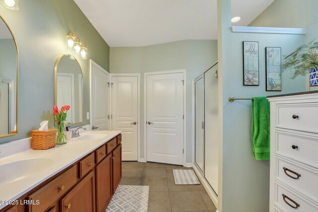 bathroom featuring tile patterned floors, a stall shower, double vanity, and a sink