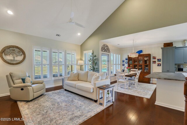 living area featuring dark wood-type flooring, baseboards, visible vents, and high vaulted ceiling