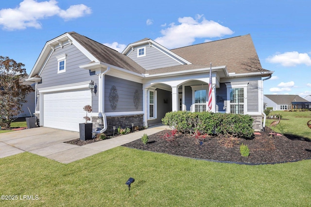 view of front of property featuring concrete driveway, stone siding, a front yard, and roof with shingles