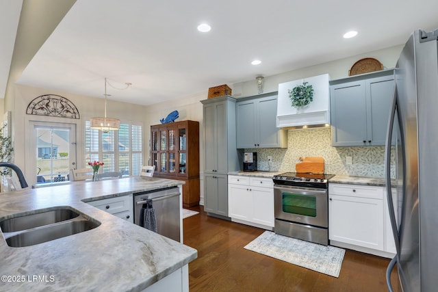 kitchen featuring dark wood finished floors, a sink, hanging light fixtures, appliances with stainless steel finishes, and tasteful backsplash