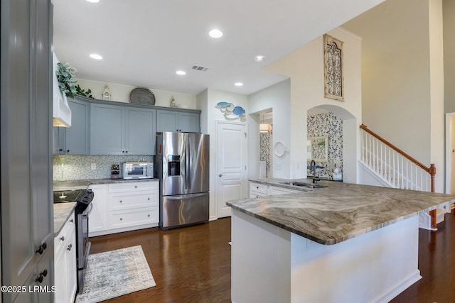 kitchen with light stone counters, visible vents, a sink, dark wood-type flooring, and appliances with stainless steel finishes