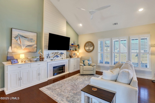 living area featuring baseboards, visible vents, dark wood finished floors, ceiling fan, and a glass covered fireplace