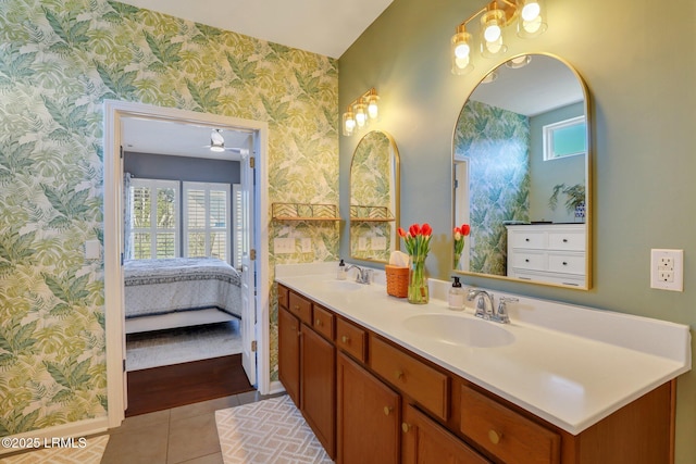 ensuite bathroom featuring a sink, double vanity, tile patterned flooring, and wallpapered walls