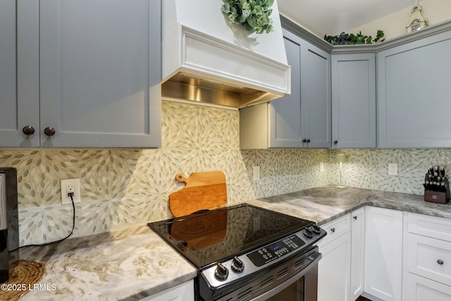 kitchen with backsplash, electric stove, custom range hood, and light stone countertops