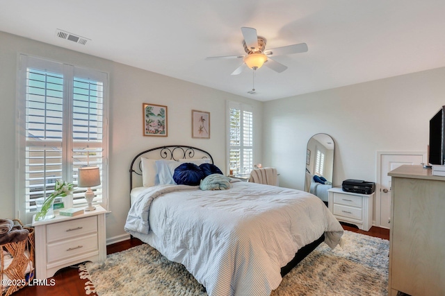 bedroom featuring visible vents, baseboards, ceiling fan, and wood finished floors