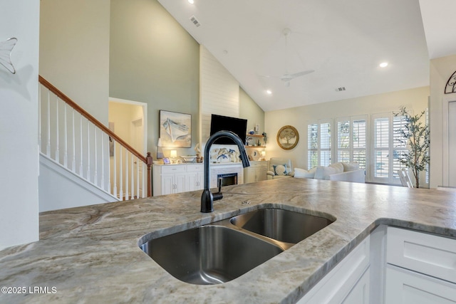 kitchen featuring light stone countertops, open floor plan, and a sink