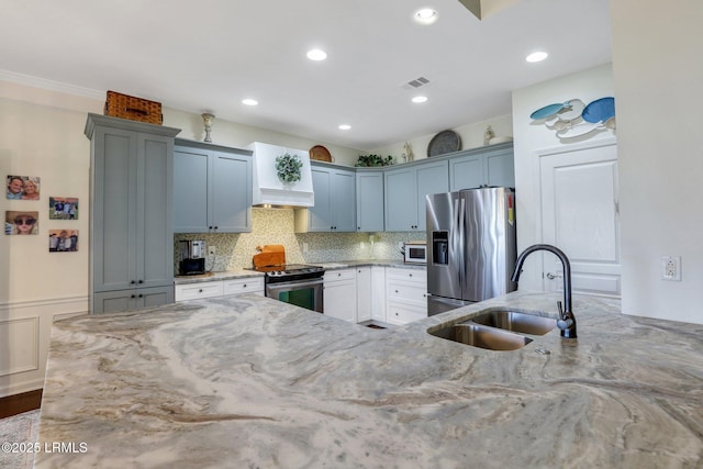 kitchen with visible vents, light stone countertops, appliances with stainless steel finishes, custom exhaust hood, and a sink