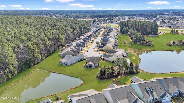 drone / aerial view featuring a wooded view, a water view, and a residential view