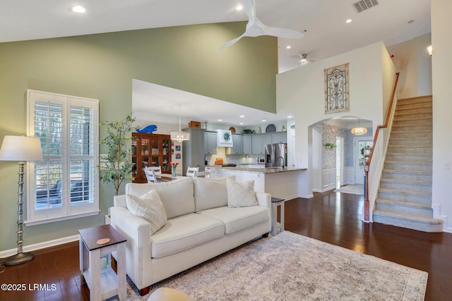 living area featuring visible vents, ceiling fan, dark wood finished floors, stairway, and high vaulted ceiling