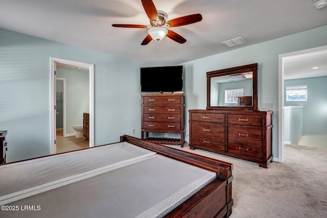 bedroom featuring a ceiling fan, light carpet, visible vents, and ensuite bath