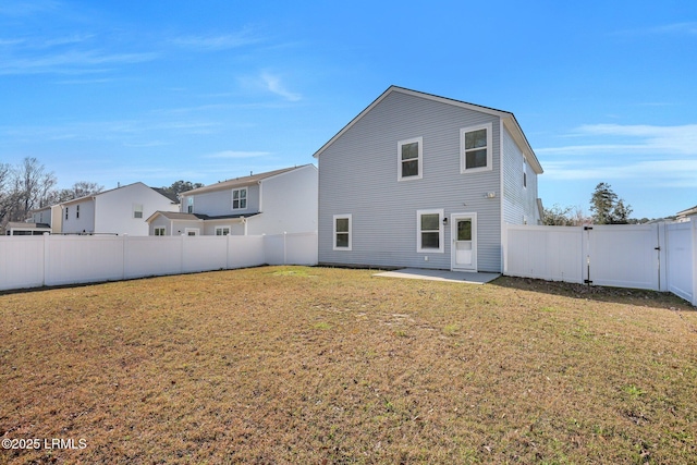 rear view of house with a lawn, a patio area, a fenced backyard, and a gate