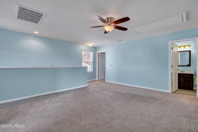 spare room with light carpet, attic access, visible vents, baseboards, and ceiling fan