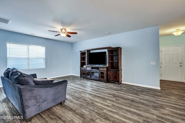 living room featuring dark wood-style floors, visible vents, baseboards, and a ceiling fan